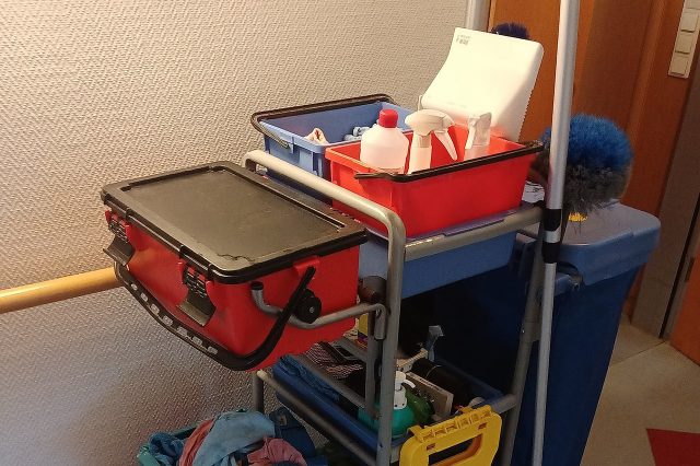 Putzwagen mit Reinigungsutensilien wie Sprühflaschen, Tüchern, Eimern und Mopp.