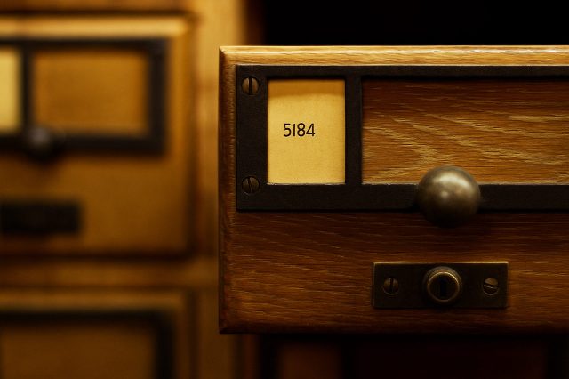 Das herausgezogene Schubfach eines hölzerenen Aktenschrankes.